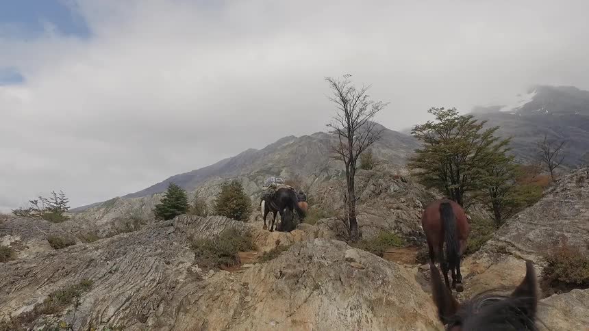 Person on horseback leads other horses up a rocky mountain