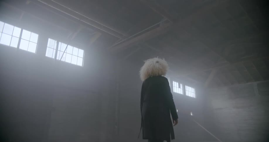 A woman is walking in an abandoned warehouse during the day