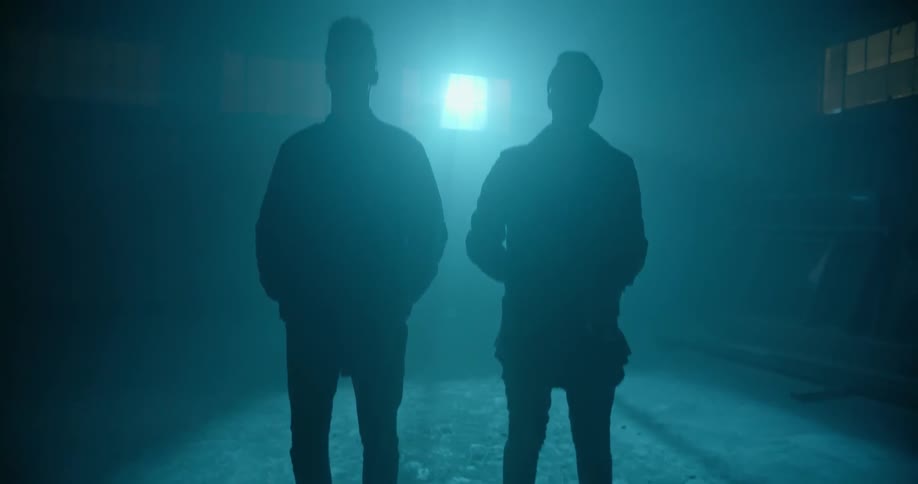 Men stand in front of a spotlight