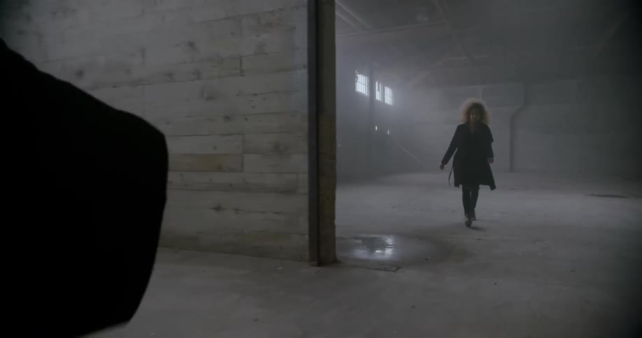 Woman walks after a person in a vacant warehouse
