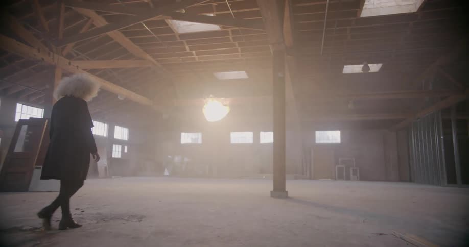 Woman walks across empty warehouse floor
