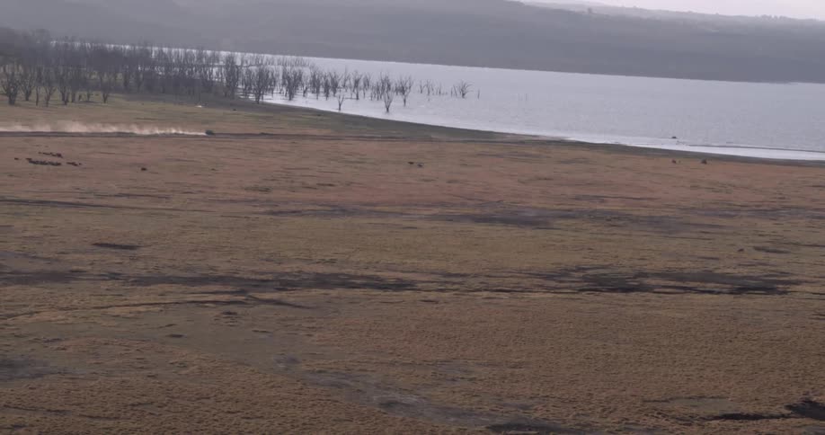 A car drives across the floodplain towards a river