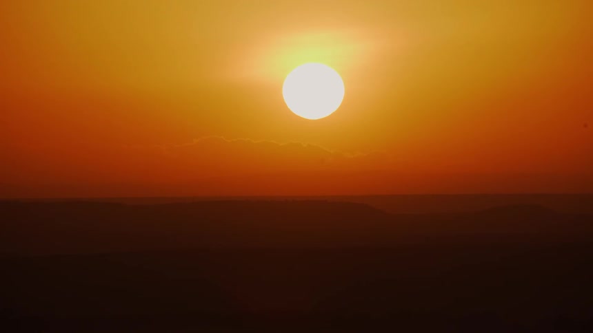 The sun is setting in an orange sky