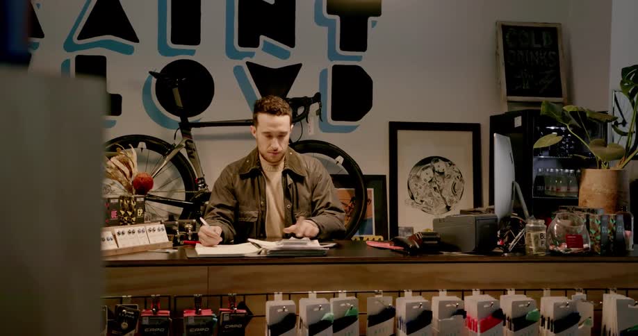 A worker at a bicycle shop balances finances in a notebook