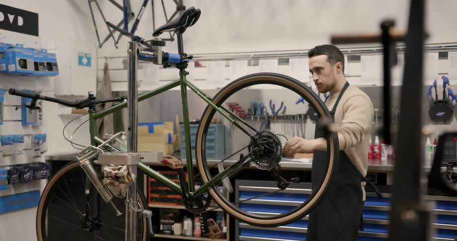 A man in a bike workshop adjusts a tyre