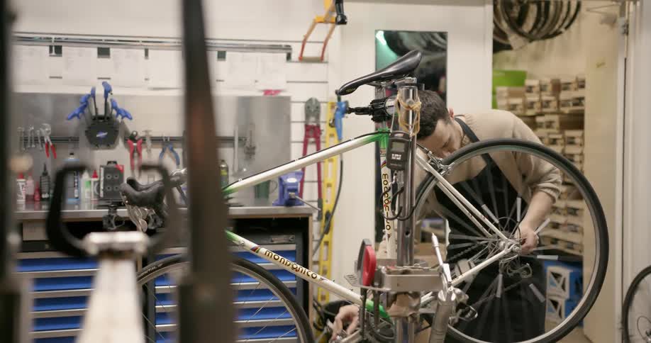 Someone is working on a bikes wheels in a shop