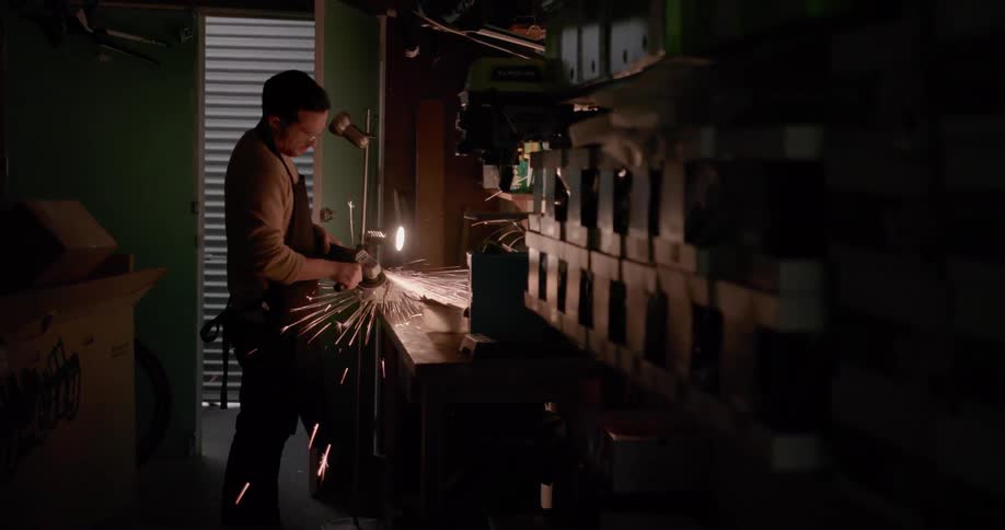 A man is using a grinder at his workstation