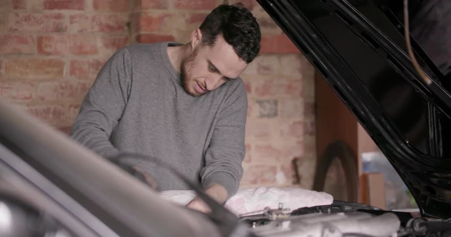 A man is working on his car engine