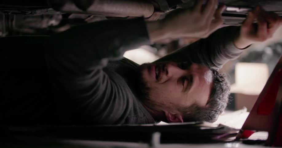 A man is working on the underside of a car