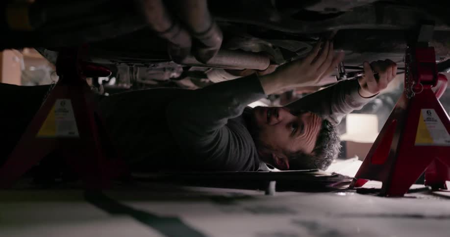 A man is working on his car from underneath