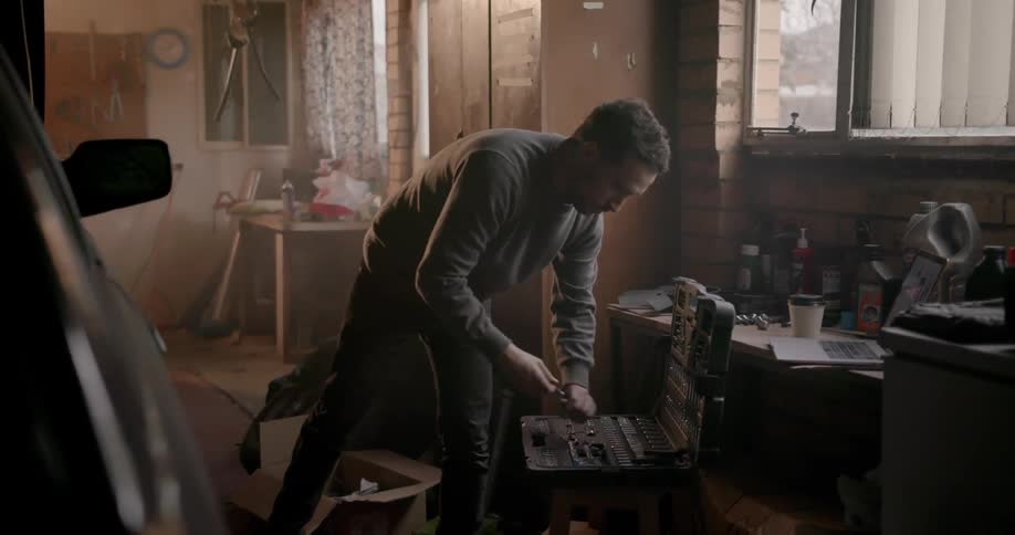 A man is opening a tool chest in a garage during the day