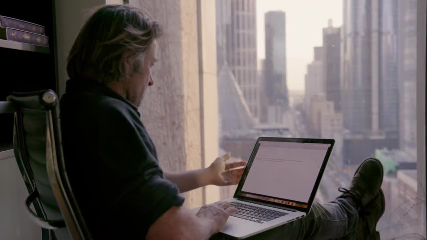 A man is using a laptop while looking out the window