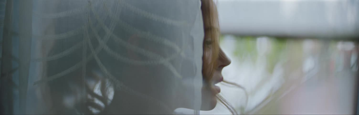 Woman Smoking A Cigarette Behind The Curtain Of An Open Window