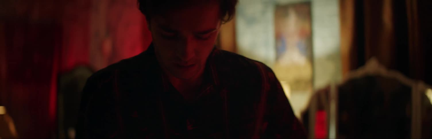 A man is upset and using his phone in a red lit room