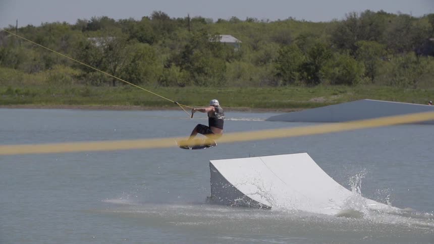 A water skier is jumping off of a ramp