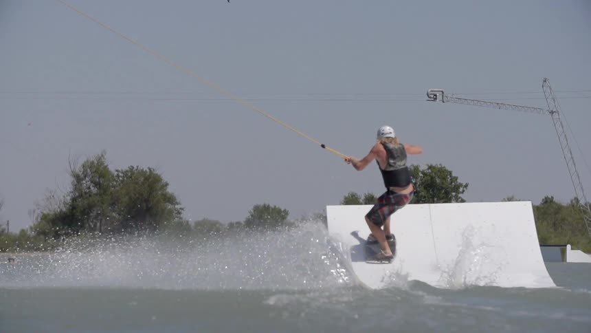 A wakeboarder approaches and completes a jump