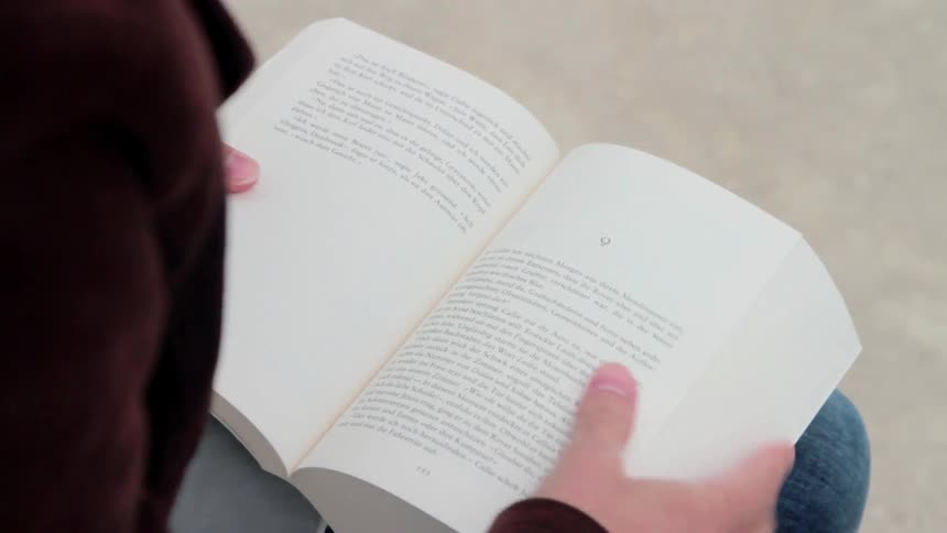 A person is reading a book outside during the day