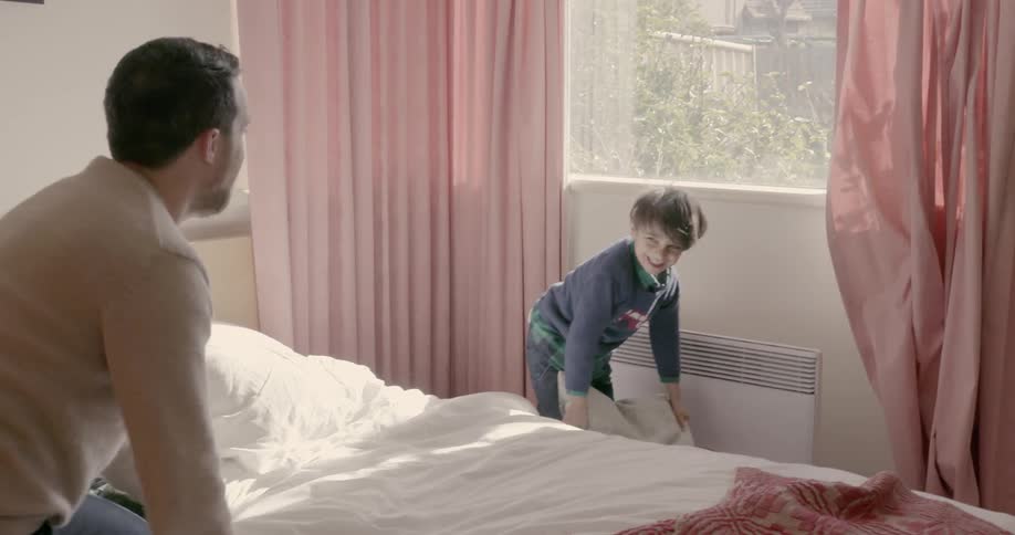 A man and boy have a pillow fight