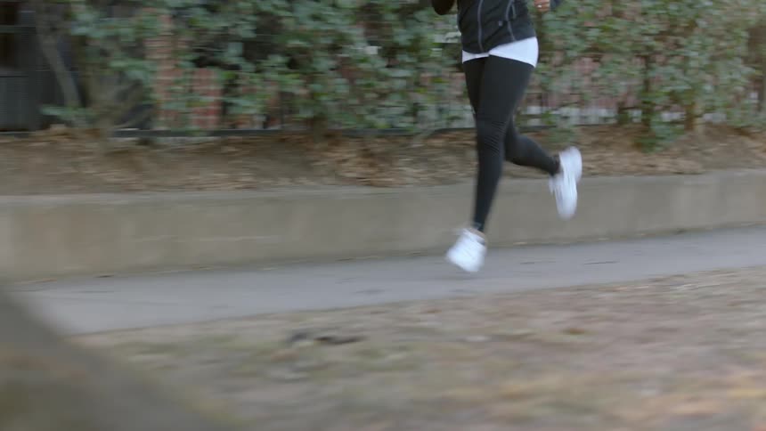 A woman jogs down a sidewalk