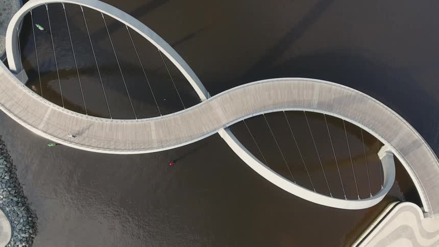 People riding bikes on spiral shaped suspension bridge