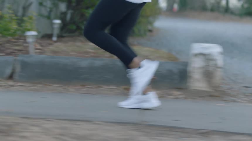 A person begins jogging on the neighborhood sidewalk