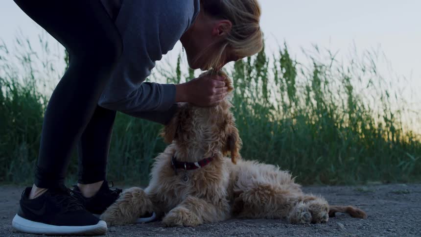 A woman pets and kisses her dog outside