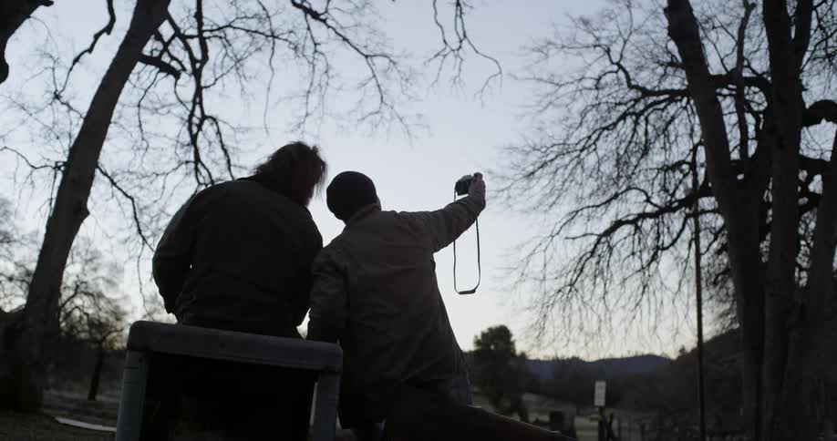 A man takes a photograph outside at dusk