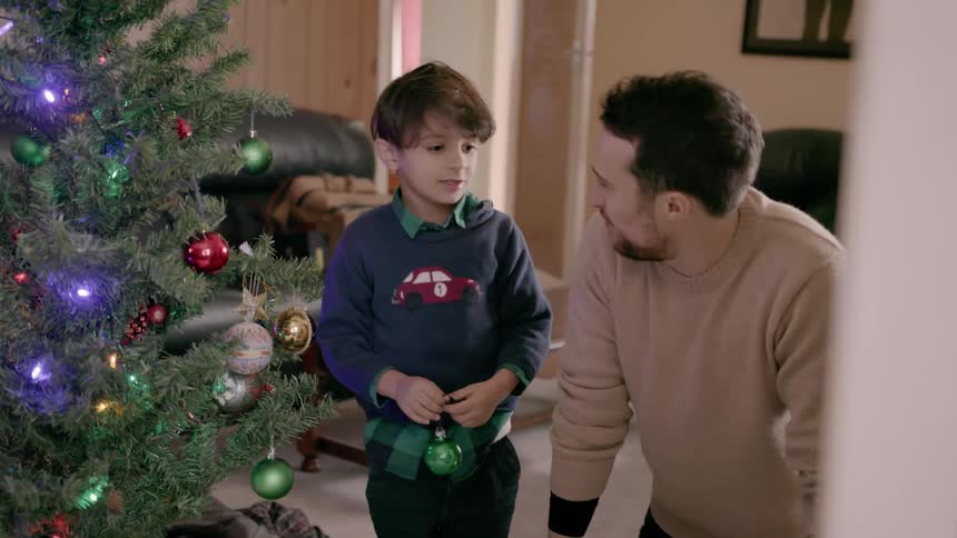 A young boy places ornaments on a christmas tree