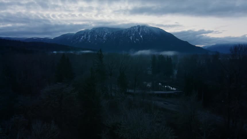 Clouds hang above a snow covered mountain