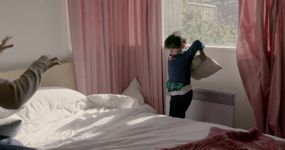 A child throws pillows at his dad