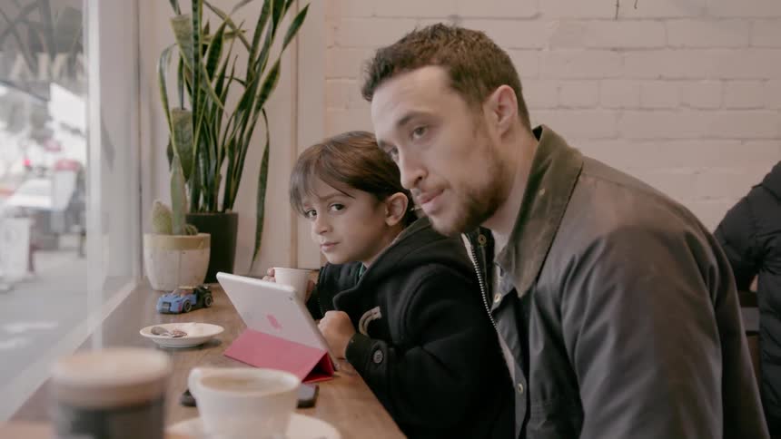 A man sits with a young boy in a cafe