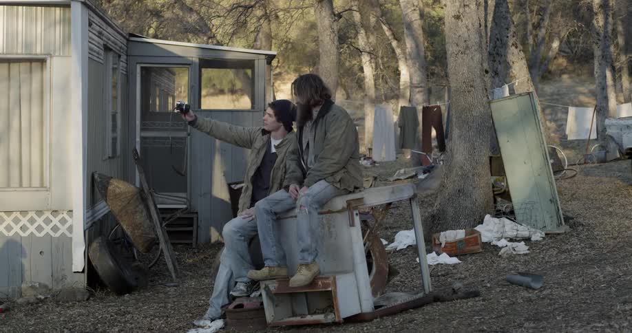 Two people are sitting in the yard and one takes a photograph
