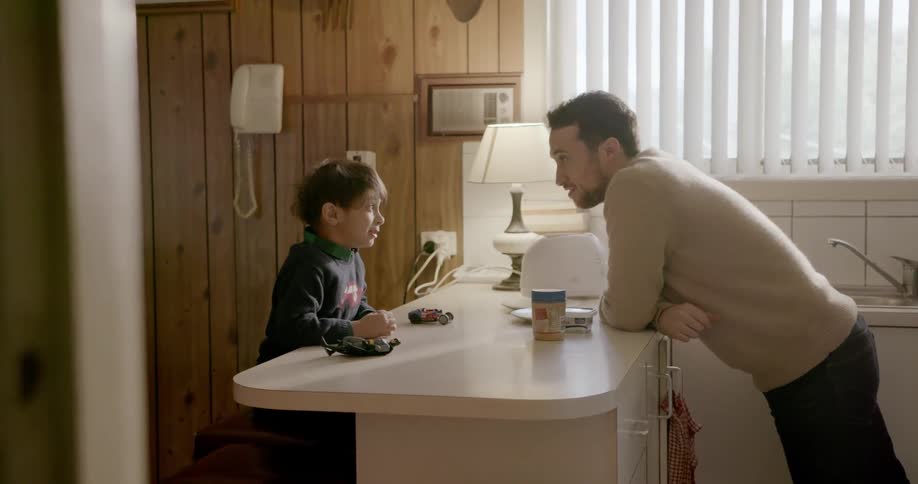 A man talks with his son at the kitchen table