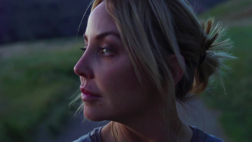 A woman looks to her side smiling at sunset