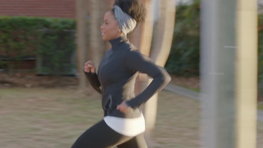A woman is jogging down the sidewalk