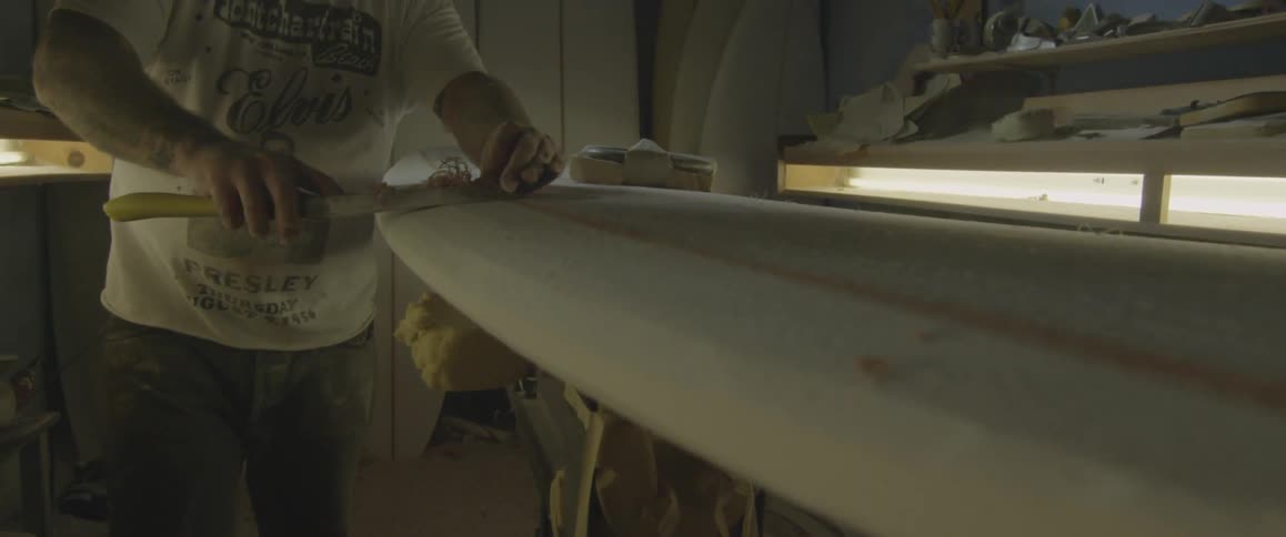 A man using a hand planer on a long piece of wood