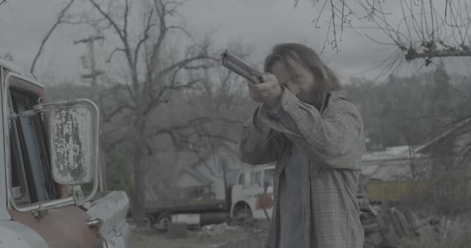 A man is holding and pointing a shotgun