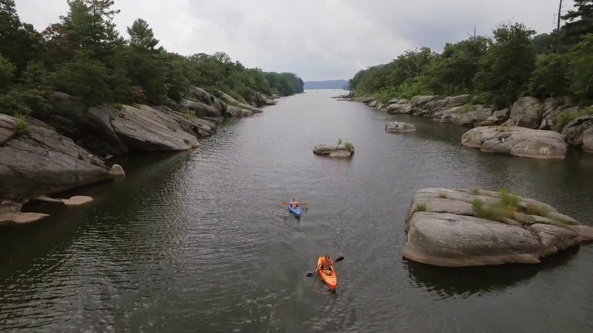 People kayak down a stream