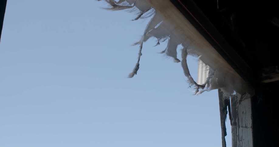 The wind is blowing the torn fabric hanging from the roof