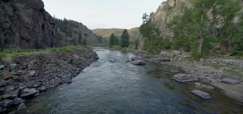 A small river is being bordered by two hills and a road
