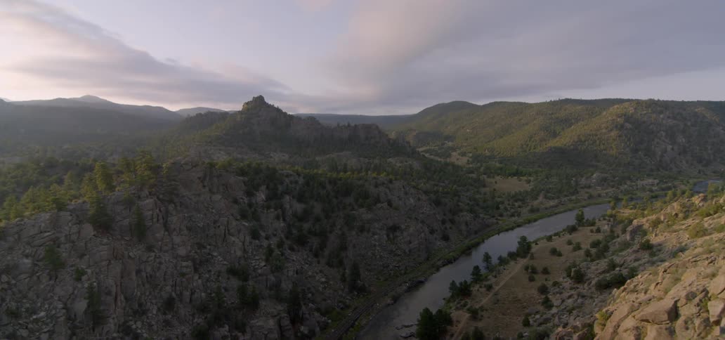 Sparse clouds hang over a stone mountain and river