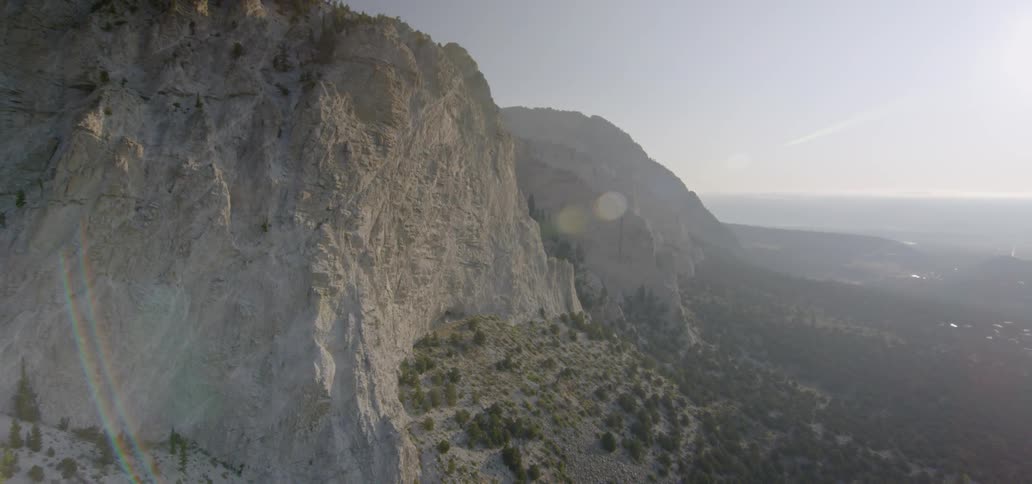 The sun shines on a tall stone mountain