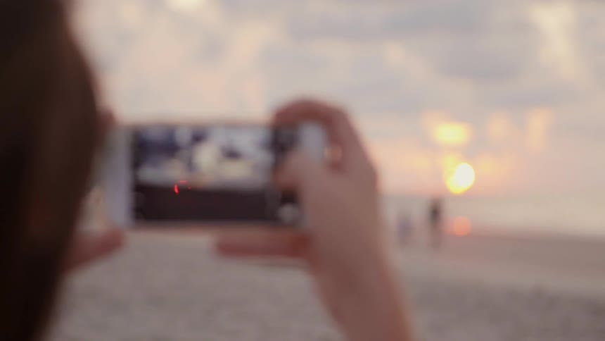 A person is taking photos of beach at sunset