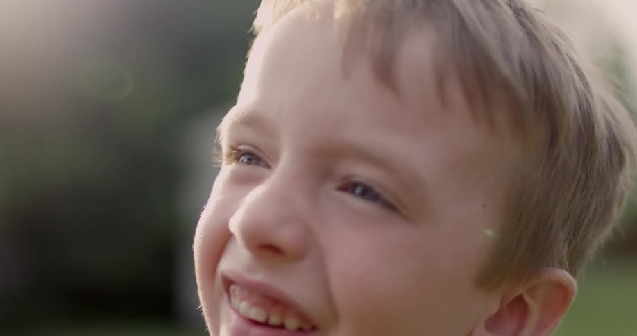 A child shades his eyes from the sun and smiles