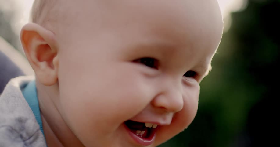 Baby laughs outside on a sunny day