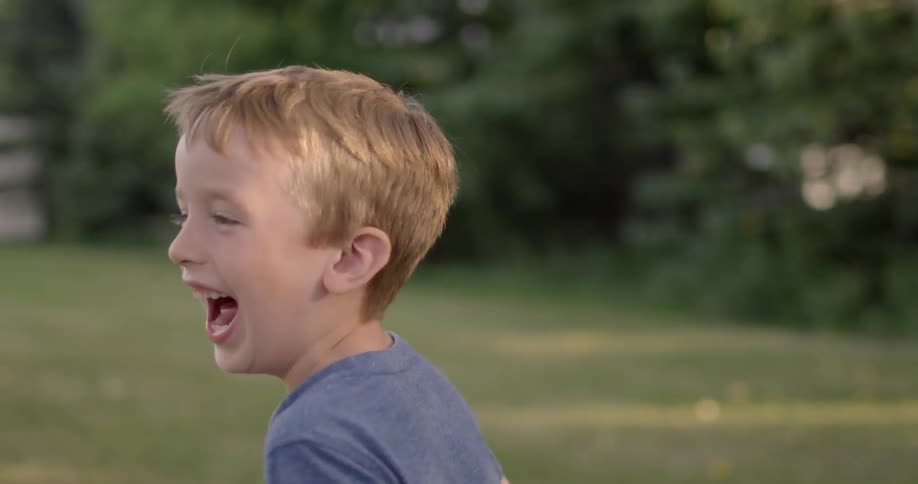 A young boy plays outside under the sun