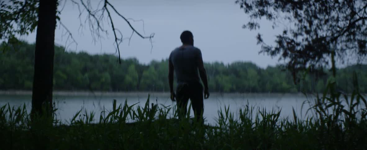 A man looks at a lake surrounded by trees
