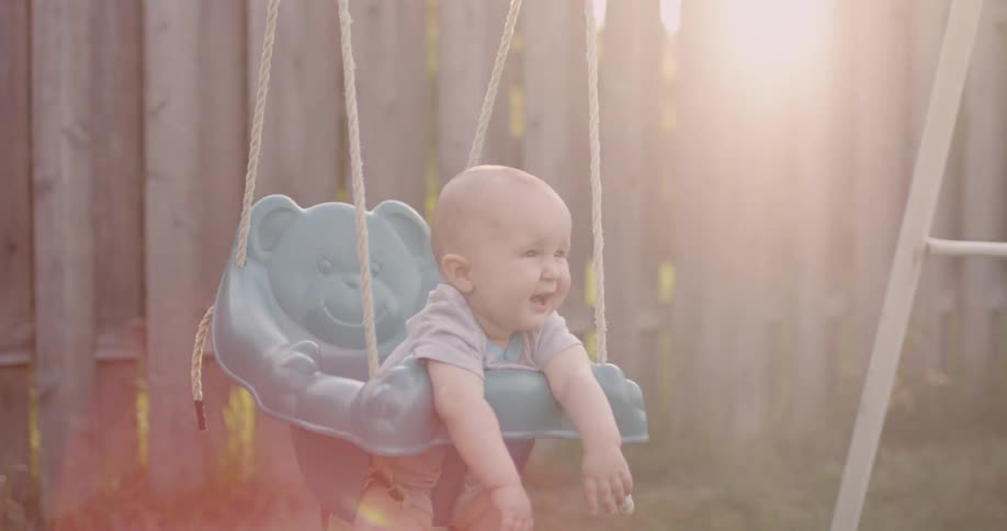 A young baby swings on an outdoor swing