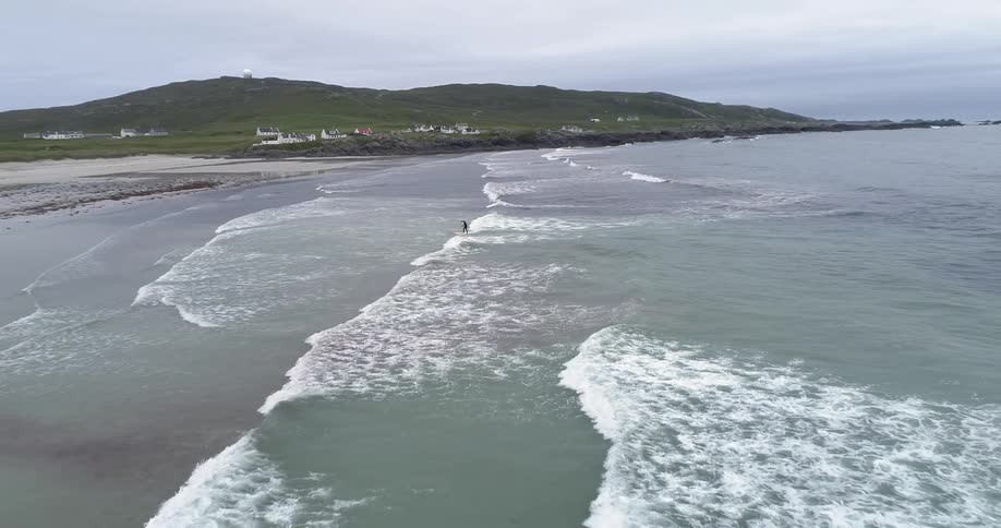 A surfer rides a wave towards the shore