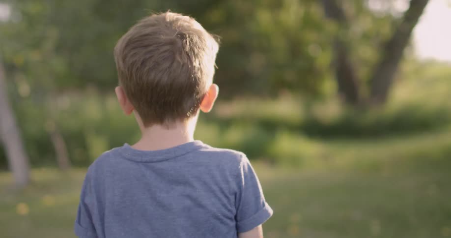 A young boy plays outside under the sun